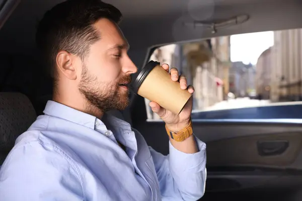 To-go drink. Handsome man drinking coffee in car, space for text
