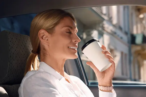To-go drink. Happy woman drinking coffee in car