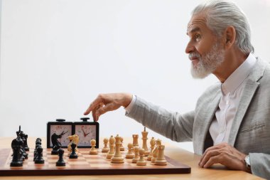 Man turning on chess clock during tournament at table against white background clipart