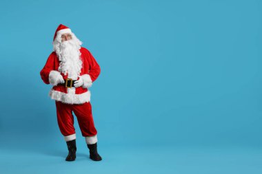 Mutlu noeller. Açık mavi arkaplanda poz veren Noel Baba, metin için boşluk