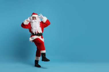 Mutlu noeller. Kulaklıklı Noel Baba açık mavi arka planda müzik dinliyor, mesaj için yer var.