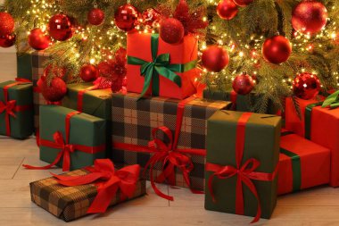 Kapalı alandaki Noel ağacının altında birçok hediye kutusu var.