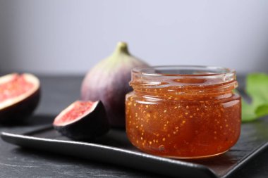 Kavanoz dolusu lezzetli incir reçeli ve siyah masada taze meyveler, yakın plan. Metin için boşluk