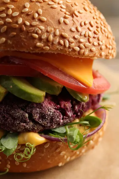 Tasty vegetarian burger with beet cutlet, cheese, avocado and tomato on table, closeup