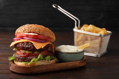 Köfteli, domatesli ve ahşap masadaki soslu lezzetli çizburger.
