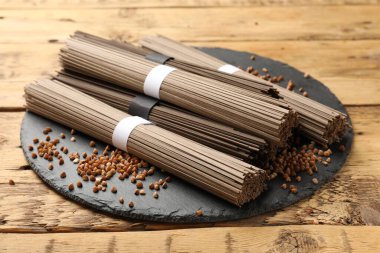 Ahşap masada pişmemiş karabuğday eriştesi (soba) ve tahıllar, yakın plan.