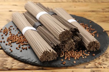 Ahşap masada pişmemiş karabuğday eriştesi (soba) ve tahıllar, yakın plan.