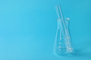 Açık mavi arka planda test tüplü matara, metin için boşluk. Laboratuvar camları.