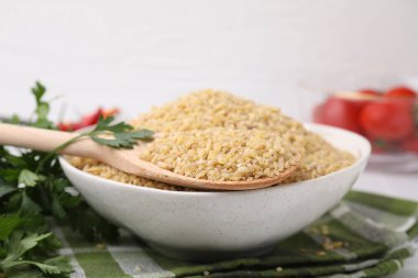 Tabakta çiğ bulgur olan kase ve kaşık, yakın plan.