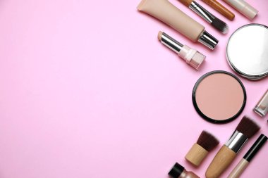 Yüz pudraları ve pembe arka planda diğer dekoratif kozmetik ürünler, düz yatak. Metin için boşluk