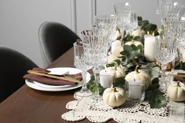 Güzel bir sonbahar sofrası. Tabaklar, çatal bıçak takımı, gözlük ve çiçek dekoru.