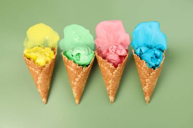 Soluk yeşil arka planda waffle külahlarında erimiş dondurma, düz uzanmış.