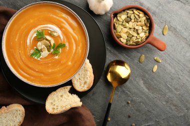 Gri desenli masada bir kase lezzetli kabak çorbası ile düz bir kompozisyon.