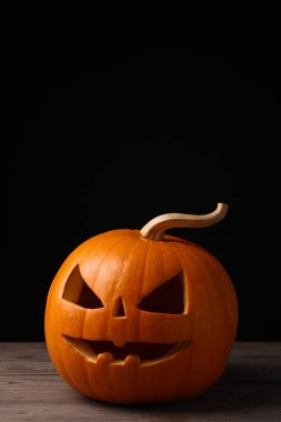 Ahşap masa üzerinde balkabağından yapılmış korkunç Jack O 'Lantern siyah arka planda, mesaj için yer var. Geleneksel Cadılar Bayramı dekorasyonu