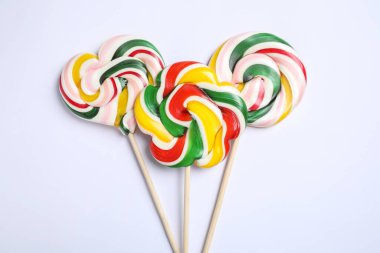 Beyaz arka planda farklı renklerde lolipopları olan çubuklar, düz yatış