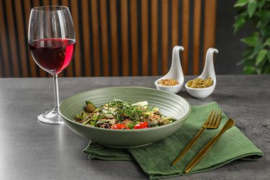 Tarhun soslu lezzetli yemekler, salata sosu ve gri masada servis edilen bir bardak şarap.