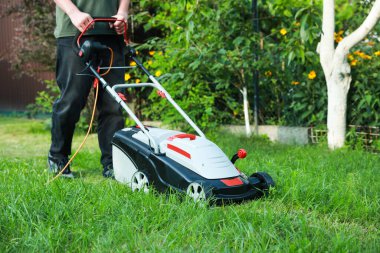 Bahçede çim biçme makinesiyle çim biçen adam, yakın plan. Metin için boşluk