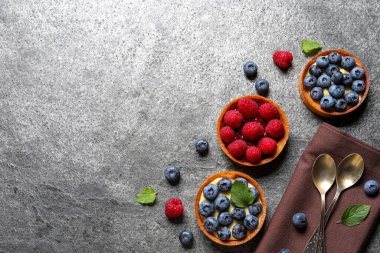 Açık gri masada farklı taze böğürtlenli turtalar, düz yatış ve metin için boşluk. Tatlı nefis.