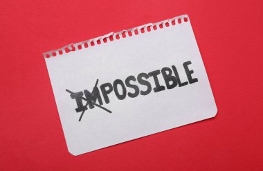 Motivasyon konsepti. Kağıt kırmızı arkaplanda I ve M harflerinin üzerinden geçerek İmkânsızdan Olanaksız 'a çevrilmiş. Üst görünüm