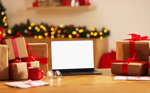 Christmas time. Laptop with blank screen, gift boxes and letters on table at home