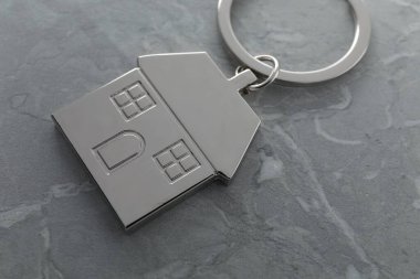 Gri mermer masada ev şeklinde metal anahtarlık, yakın plan.
