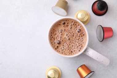 Bir fincan kahve ve kapsüller ışık masasında, düz yerde. Metin için boşluk