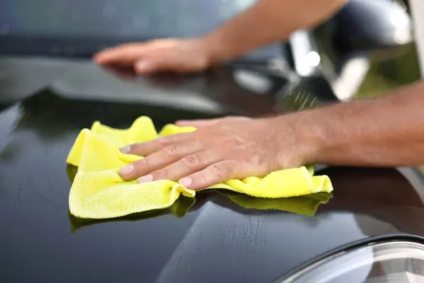 Man washing car hood with rag outdoors, closeup