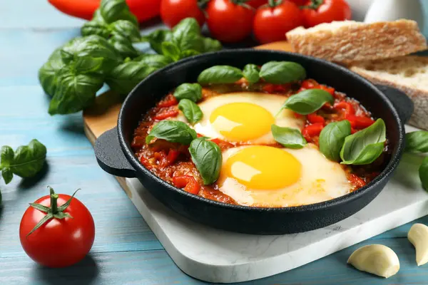 Lezzetli Shakshuka, açık mavi ahşap masada servis yapıyor, yakın plan.