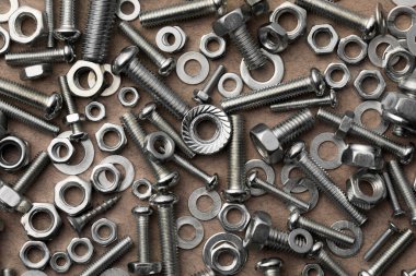 Bej desenli sehpada farklı metal cıvatalar ve fındıklar var.