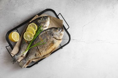 Deniz ürünleri. Hafif desenli masada yeşil soğan ve limonla servis edilen nefis pişmiş balık, üst manzara. Metin için boşluk