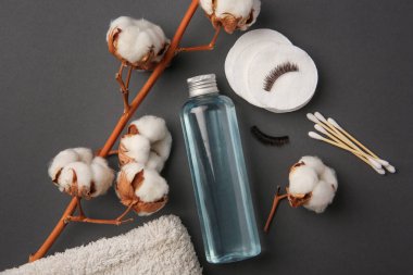 Gri arka planda bir şişe makyaj çıkarıcı ile düz bir kompozisyon.