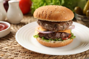 Hasır üzerinde köfteli, peynirli ve sebzeli lezzetli hamburger, yakın plan.