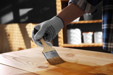 Fırçalı bir adam ahşap zemine ahşap leke sürüyor. Kapalı alanda, yakın plan.