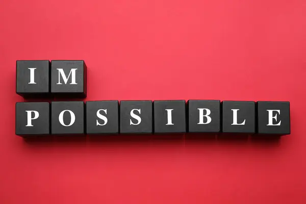 Motivation concept. Changing word from Impossible into Possible by removing black wooden cubes on red background, flat lay