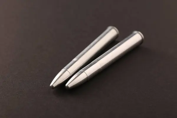 Two metal bullets on black background, closeup