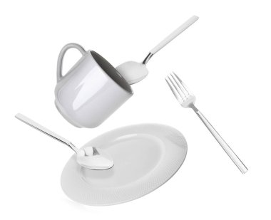 Temiz tabak, fincan ve çatal bıçak takımı beyaz arka plana düşüyor.