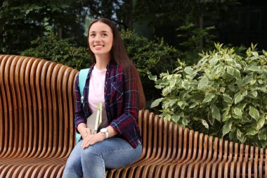 Bankta not defterleri olan mutlu genç bir öğrenci. Metin için yer var.