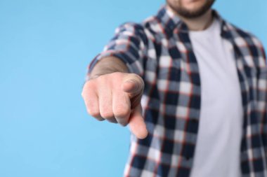Açık mavi arkaplanda işaret parmağı olan adam, yakın plan