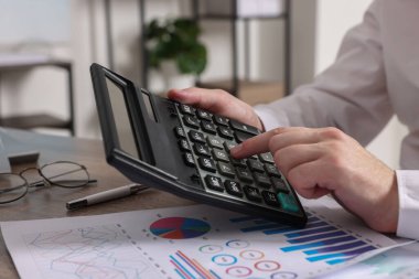 Ahşap masada hesap makinesi kullanan adam, yakın plan.