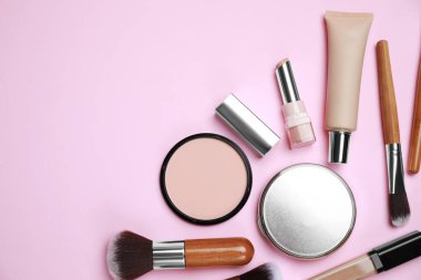 Yüz pudraları ve pembe arka planda diğer dekoratif kozmetik ürünler, düz yatak. Metin için boşluk