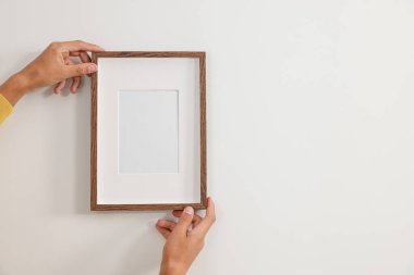 Genç adam içerideki beyaz duvara resim çerçevesi asıyor, yakın plan. Metin için boşluk