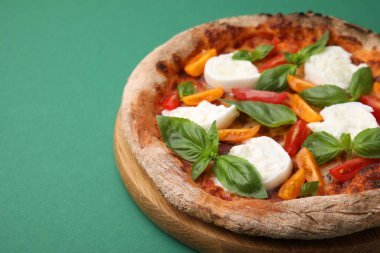 Burrata peynirli lezzetli pizza, yeşil arka planda domates ve fesleğen, yakın plan. Metin için boşluk