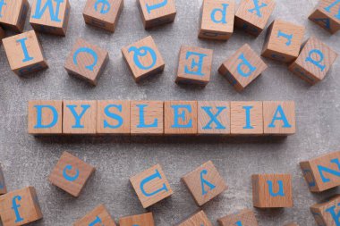 Açık gri taş masada kelime disleksisi olan tahta küpleri düz yatıyordu.