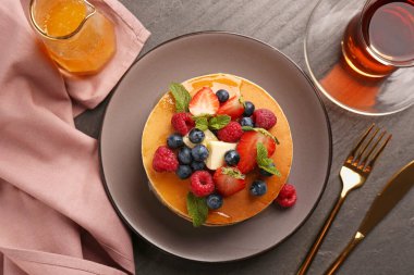 Gri masada servis edilen taze böğürtlenli, bal ve tereyağlı leziz gözlemeler.