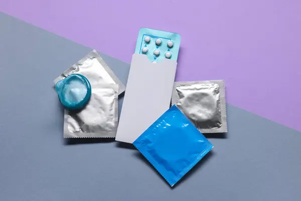 Condoms and birth control pills on color background, flat lay. Choosing method of contraception