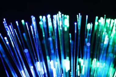 Optik fiber iplikler siyah arkaplanda farklı renk ışıkları iletiyor, yakın plan