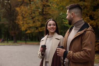 Romantik genç çift, sonbahar parkında birlikte vakit geçiriyorlar.