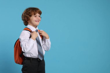 Açık mavi arka planda sırt çantalı mutlu okul çocuğu, mesaj için yer