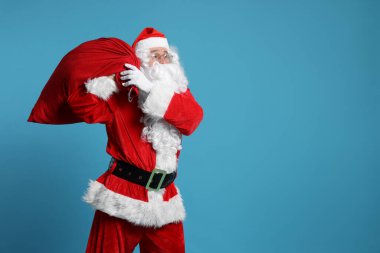 Noel Baba 'nın açık mavi arka planda bir çanta dolusu Noel hediyesi, mesaj için boşluk