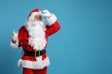 Mutlu noeller. Açık mavi arkaplanda poz veren Noel Baba, metin için boşluk